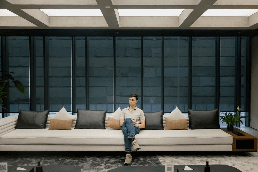 Alex Scott seated on a long sofa in a light-filled lounge